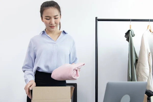 Young Asian women pack their clothes into boxes and prepare them to be delivered by post, Online clothing sales business, Business of selling clothes on social media or selling online.