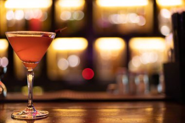 Çilek suyu, alkollü gazozla karıştırılmış. Şarap barının önündeki kokteyl bardağında. Arka plan görüntüsü açık turuncu..