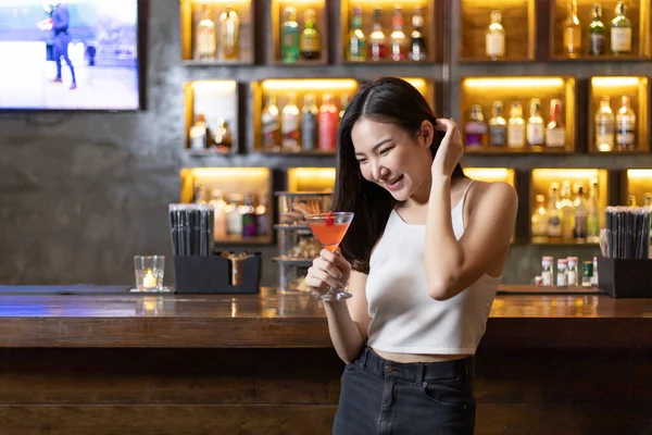 Asian alone women enjoy cocktails in front of a vintage bar, Relaxing activities after work or hangouts, Place of entertainment for young adolescents or night club party.