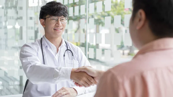 Two men holding hands, Asian doctor smiled shake hands with the patient congratulating him on being healthy and strong, Successful treatment, Hold hands, Handshake, shook hands.