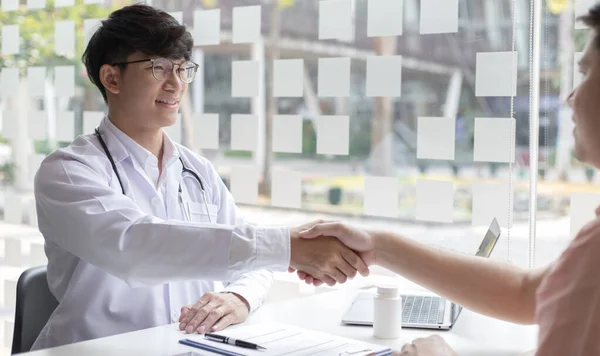 Two men holding hands, Asian doctor smiled shake hands with the patient congratulating him on being healthy and strong, Successful treatment, Hold hands, Handshake, shook hands.