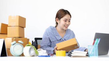 Genç Asyalı kadın, müşterinin bilgilerini ve adreslerini posta kutusuna yazıp bilgilere göre nakliyeye hazırlanıyor..