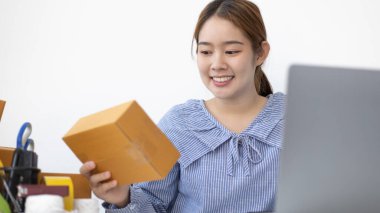 Elinde posta kutusu olan gülümseyen Asyalı kadın bir şeyler teslim etmeye hazırlanıyor, iş sahibi evden çalışıyor, sipariş almak ve siparişlerini internetten onaylamak için dizüstü bilgisayar kullanan gençler için iş kuruyor..