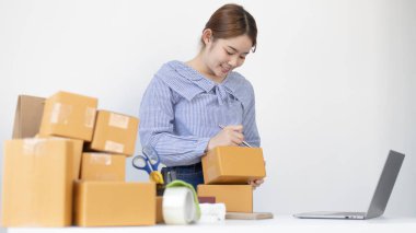 Genç Asyalı kadın, müşterinin bilgilerini ve adreslerini posta kutusuna yazıp bilgilere göre nakliyeye hazırlanıyor..