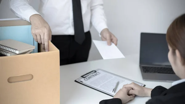 Employee handed over a document envelope and a box of work equipment beside him, Businessman submits resignation documents to their supervisor and take personal equipment in a brown box from the office.