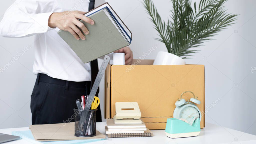 Put the work equipment in the office in a large brown box, Businessmen are keeping work documents and personal belongings due to resignation or being fired, termination of employment.