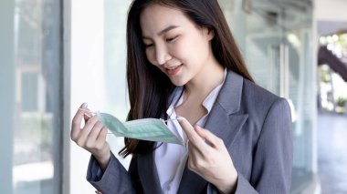 Genç Asyalı kadının takmaya hazır bir maskesi var. CORONA VIRUS 'un patojen ya da salgınlarının önlenmesi, ilk koruma. Mikropların yayılmasını azaltmaya yardım etmek, yüz maskesi, önce güvenlik.