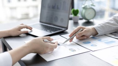 Beyin fırtınası ekibi, pazarlamacılar ve finans muhasebecileri müşteri ihtiyaçlarını karşılamak için stratejiler planlamak, grafikler ve dizüstü bilgisayarları kullanarak iş verilerini analiz etmek ve konsepti karşılamak için grafikleri tartışıyor ve analiz ediyorlar..