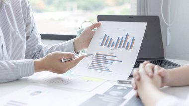 Beyin fırtınası ekibi, pazarlamacılar ve finans muhasebecileri müşteri ihtiyaçlarını karşılamak için stratejiler planlamak, grafikler ve dizüstü bilgisayarları kullanarak iş verilerini analiz etmek ve konsepti karşılamak için grafikleri tartışıyor ve analiz ediyorlar..