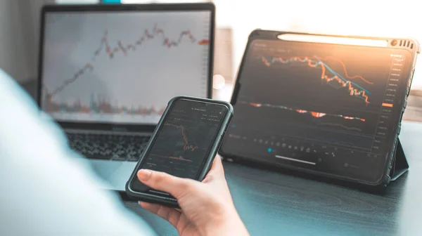 Hand of a young business woman holds a phone with a graph of the stock market data and analyzes the stock market gain and loss, do this deal on a stock exchange, Analysis of stock market data.