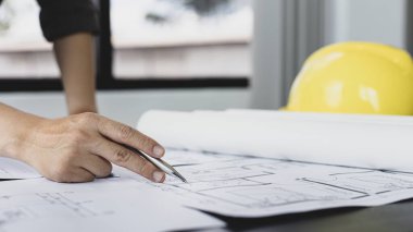 Mimari bina tasarımı ve planlı inşaat planları, genç adam cetvel, kalem, mezura, mimar şapkası ve diğer ekipmanlarla bir bina veya mimari tasarlıyordu..