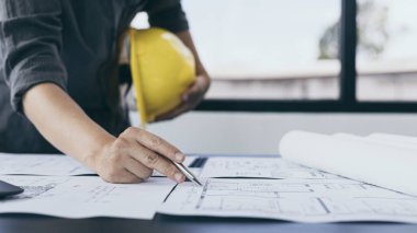 Mimari bina tasarımı ve planlı inşaat planları, genç adam cetvel, kalem, mezura, mimar şapkası ve diğer ekipmanlarla bir bina veya mimari tasarlıyordu..