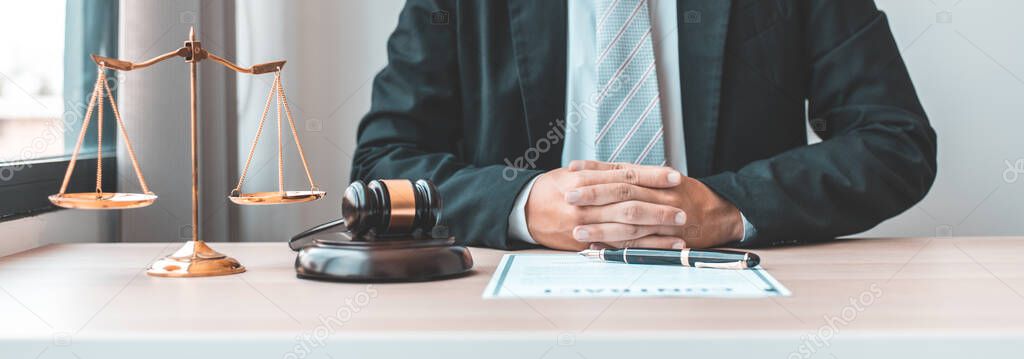 Male lawyer or judge sits and analyzes the case and decides the case with fairness, On the table were the scales of justice and the hammer of honest judgment, Concepts of Law and Legal services.