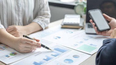 İş beyin fırtınası, kadın pazarlamacı yöneticilerle grafik verilerini analiz ediyor ve şirket performansını bir konferans odasında izlemek için bir cep telefonu kullanıyor, iş ekibi toplantısı.