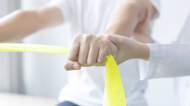 Fizyoterapi, kadın fizyoterapist, kliniğe giden bir erkeğin kol yaralanmasını, kemik düzenini, cerrahi olmayan tıbbi tedaviyi ve tıbbi teknikleri test etmek için elastik bant kullanıyor..