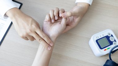 Tıbbi uzman, erkek bir hastanın bileğinin nabzını ölçerek hastane muayene odasında nabzını ölçer, doktor hasta sağlığını kontrol eder, ilk semptomları kontrol eder..