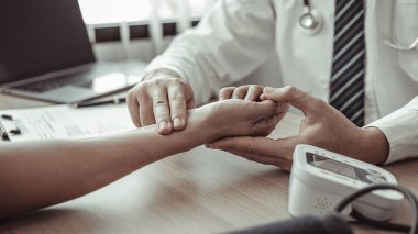 Tıbbi uzman, erkek bir hastanın bileğinin nabzını ölçerek hastane muayene odasında nabzını ölçer, doktor hasta sağlığını kontrol eder, ilk semptomları kontrol eder..