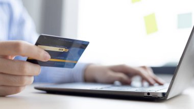Kadının parmağı bir klavyeye basıyor ve ödeme veya çevrimiçi işlemler, mali işlemler ve İnternet güvenliği, İnternet üzerinden alışveriş ve bankacılık konseptini kaydetmek için kredi kartı tutuyor.