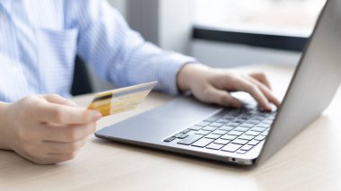 Kadının parmağı bir klavyeye basıyor ve ödeme veya çevrimiçi işlemler, mali işlemler ve İnternet güvenliği, İnternet üzerinden alışveriş ve bankacılık konseptini kaydetmek için kredi kartı tutuyor.