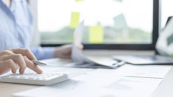 Young Asian businesswoman presses a calculator to calculate income tax and corporate income in a private office, Finance, Accounting, Tex, Statistical graphs of marketers investing in real estate.