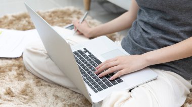 Not defterine not alan Asyalı kadın evde dizüstü bilgisayar, görüntülü sohbet, online iletişim, Evde kal, Yeni Normal, Covid-19 Coronavirus, Sosyal Mesafe, Çevrimiçi Öğren.