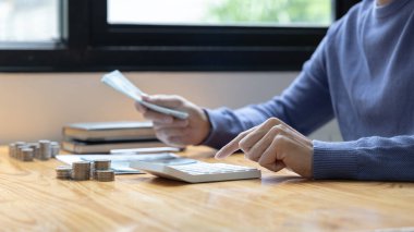 Adam yıl boyunca biriktirdiği miktarı hesaplamak için hesap makinesine basıyor, dolar banknotunu tutuyor, gelecek için para biriktiriyor, iş yatırımı, finans ve muhasebe..