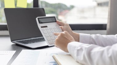 İşadamı, şirketin gelirlerini hesaplamak ve özel ofisindeki gelirleri, finans ve muhasebe bilgilerini, şirket performansını ve gelirlerini analiz etmek için hesap makinesine baskı yapıyor..