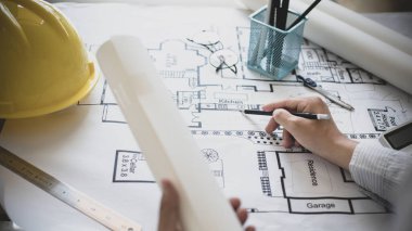 Mimari bina tasarımı ve planlı inşaat planları, kalem cetveli, kalem mezuralı, mezuralı, mimar şapkalı ve diğer ekipmanlı bir bina ya da mimari tasarım yapıyordu..