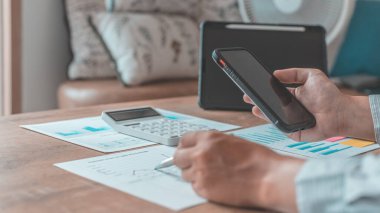 İşadamı finansal verileri incelemek ve şirket büyüme grafiklerini analiz etmek için bir cep telefonu kullanır, akıllı telefon teknolojisinin iş başında kullanımı, Gelir İçgörüsü Grafiği, Finans, Muhasebe, Vergi Sistemi, Vat.