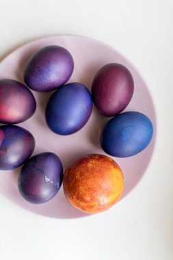 Renkli arka planda mavi ve mor paskalya yumurtaları. Tabakta paskalya yumurtası.
