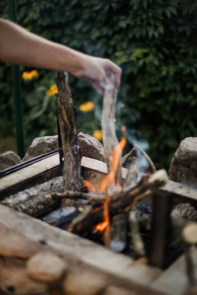 Bonfire lighted from wood in the grill at their summer cottage. Bright flame from the fire. A man lights a bonfire. Hands by the fire