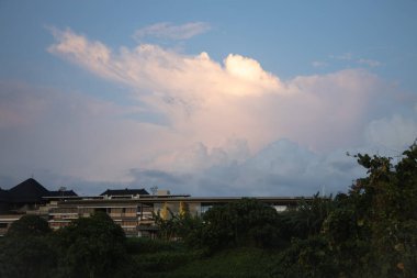 Bali 'de okyanusun kenarında inanılmaz güzel bir gün batımı. Parlak güneş suda batıyor. Güneş ışınları bulutların arkasından süzülüyor ve gün batımının suda güzel bir yansıması.
