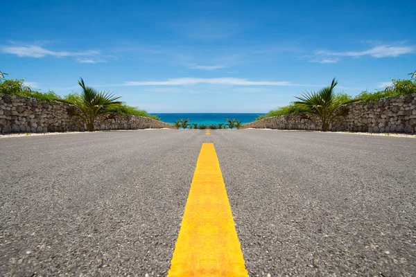 Straße mit gelber Linie endet im tropischen Meer, Ozean lizenzfreie Stockfotos