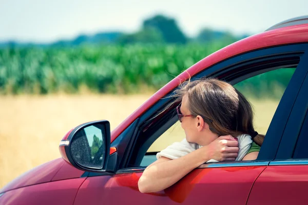 Schönes Mädchen, mit modischer Sonnenbrille, die aus dem Auto schaut Stockfoto