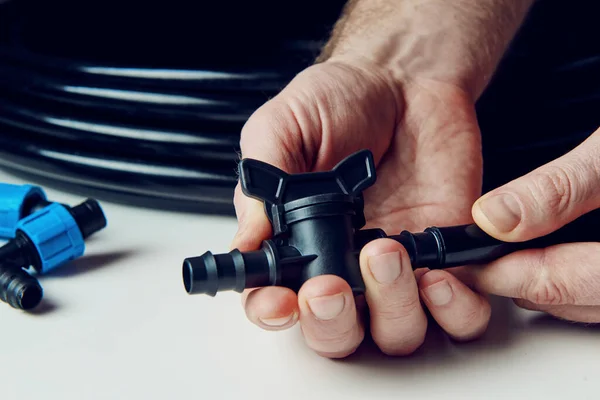İlkbaharın başında ekime hazırlanıyorum. Çerçevedeki erkek eller damlama sulama için musluğu tutuyor. DIY damlatma sulama sistemi montajı. Metin için boşluk