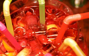 Yaz, buzlu soğuk içecek, meyveler ve pipetler, yakın çekim, yumuşak odaklanma. Renkli kokteyl tüpleri olan büyük bir kabın içinde sangria, seçici yumuşak odak, yakın çekim.