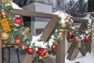 Kış, ahşap çitlerin Noel dekoru ladin dallarıyla süslenmiş oyuncaklar ve renkli toplarla