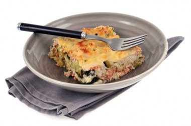 Beyaz arka planda yakın planda servis edilen ev yapımı lazanya dilimi. 