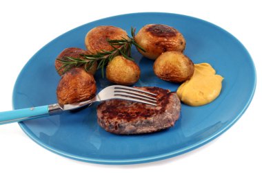 Beyaz arka planda servis edilen patates ve hardallı kıymalı biftek. 