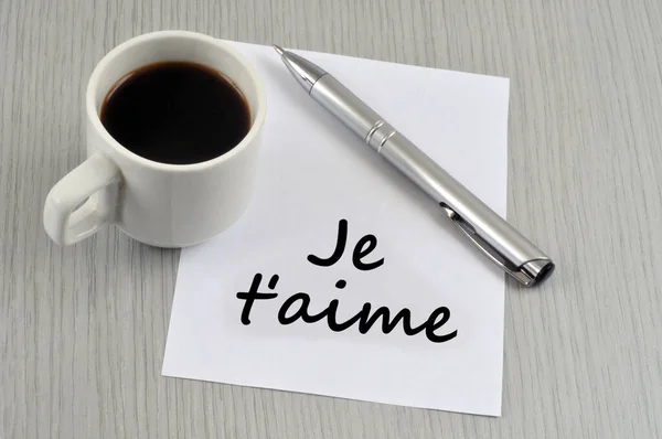 我爱你 在一杯咖啡旁边的一张纸上用法语写着 — 图库照片