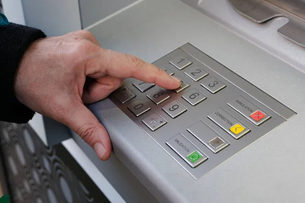 Close-up of someone making their secret code on the keypad of an ATM