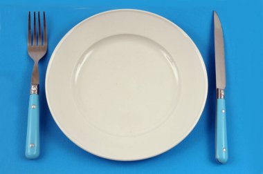 Mavi arkaplanda tabak ve çatal bıçak takımı