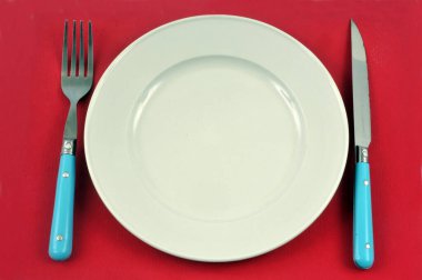 Kırmızı arkaplanda tabak ve çatal bıçak takımı