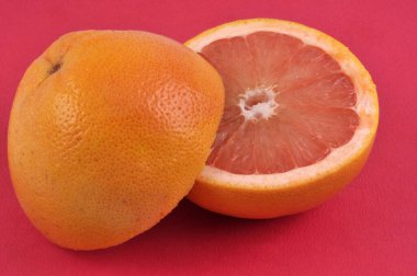 Pomelo kırmızı arkaplanda yakın plan görüntüsünü kesiyor 