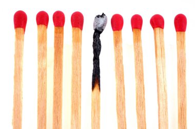 Beyaz arkaplandaki yeni kibritler arasında yanmış bir eşleşme