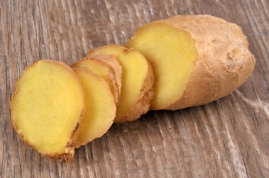 Taze zencefil, tahta arka planda yakın plan dilimlere bölünmüş. 