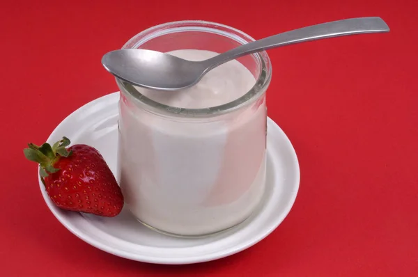 Erdbeerjoghurt Mit Einem Löffel Einer Untertasse Nahaufnahme Auf Rotem Hintergrund — Stockfoto