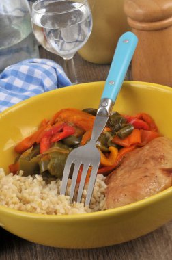 Escalope de poulet avec du boulgour et des poivrons cuits servie dans une assiette en gros plan