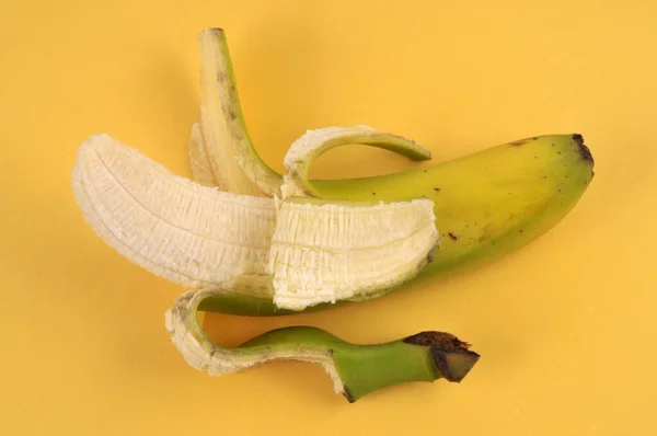 黄色の背景に半皮のバナナのクローズアップ — ストック写真