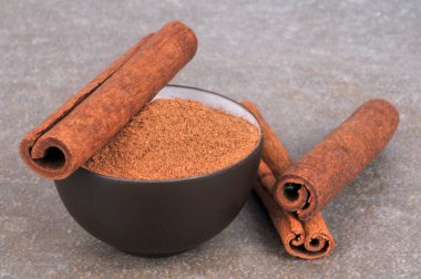 Tarçın çubukları ve tarçın tozu. Gri arka planda yakın plan.